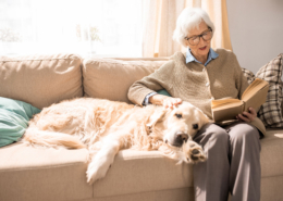 Frau mit Hund und Buch auf dem Sofa